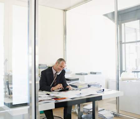 Man on the phone at desk covered in papers