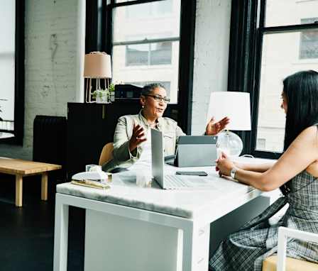 Female financial advisor in discussion with mature female business owner at desk in office