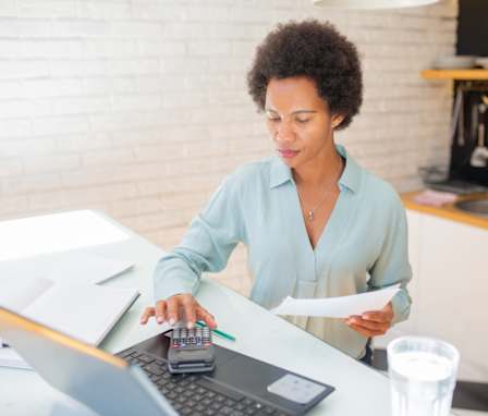 Mid adult woman using a laptop and going through paperwork