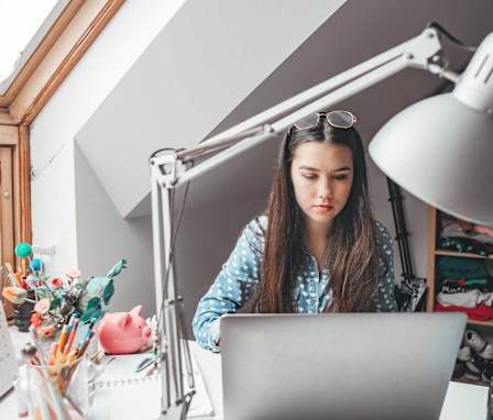 Student working on laptop with calculator